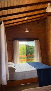 1 dormitorio con 1 cama y ventana grande en Casa do bosque, en Conceição da Ibitipoca