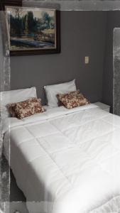 a large white bed with two pillows on it at Apto Praia da Enseada 4 pessoas in Guarujá