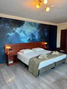 a bedroom with two beds and a large painting on the wall at Hotel Restaurant Hestia in Eijsden