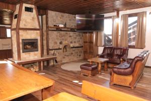 sala de estar con chimenea de piedra y muebles de cuero en Vila Toplika, en Kara Agach
