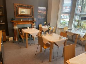 un restaurante con mesas, sillas y un piano en Monico Guest House, en Scarborough