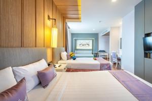 a hotel room with two beds and a television at Royal Rattanakosin Hotel SHA Plus in Bangkok