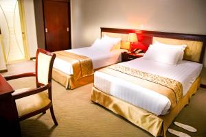 ein Hotelzimmer mit 2 Betten und einem Stuhl in der Unterkunft Hill View Hotel Kiyovu in Kigali