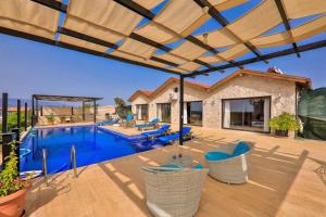 un patio con una piscina con sillas y una sombrilla grande en Villa Yaren / Kalkan, en Kas
