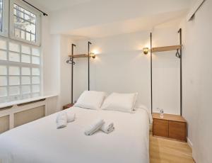 sypialnia z białym łóżkiem i 2 parami kapci w obiekcie Marais - Modern apartment w Paryżu