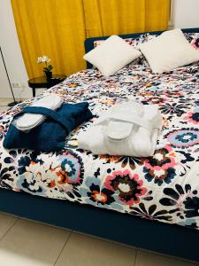 a bed with a floral comforter and pillows on it at Le Pretty Spot - Studio à Bobigny in Bobigny