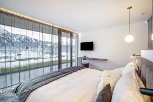 a bedroom with a bed and a large window at Golden Hill Apt Enjoy in Dobbiaco