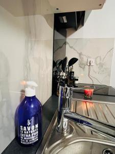 a blue bottle of soap sitting on top of a sink at Pretty Studio à Bobigny in Bobigny