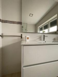 a white kitchen with a sink and a mirror at Casa Rivela do Campo in Bela Vista