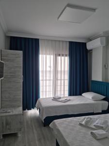 a hotel room with two beds and blue curtains at Choras Butik Otel in Şarköy