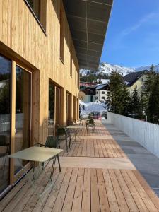 a wooden deck with tables and chairs on a building at Hideaway Planneralm operated by JUFA Hotels in Planneralm