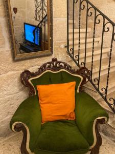 een groene stoel met een oranje kussen voor een spiegel bij Charming Central Townhouse in Sliema steps from Promenade and Sliema Ferry in Sliema