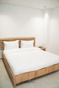 1 cama con sábanas blancas y marco de madera en Hôtel Suisse Tunis en Túnez