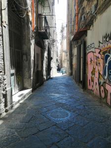 un vicolo con graffiti sul lato di un edificio di Francesco Home a Napoli