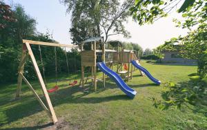 un parque infantil con 2 columpios y un tobogán en The Treehouse Gistel, en Gistel