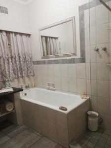 uma casa de banho com uma banheira, um chuveiro e um espelho. em Parksig Self Catering em Musina
