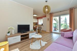 sala de estar con sofá púrpura y TV en Apartment Luka 1481, en Medulin