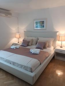 1 cama blanca grande en una habitación con 2 lámparas en Apartments Ivica, en Podstrana