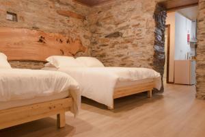 two beds in a room with a stone wall at Casa Do Peirão 