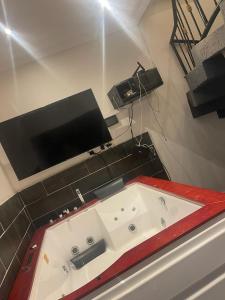 a bathroom with a bath tub with a television on the wall at Furnished house of Véranda groupe in Niamey