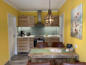 eine Küche mit gelben Wänden sowie einem Tisch und Stühlen in der Unterkunft Ferienhaus Eichhörnchen in Zossen