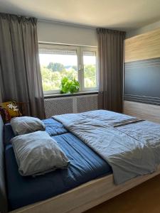 a bedroom with a large blue bed with a window at Ferienwohnung Wiesenblick in Illingen
