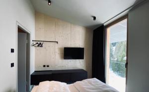 a bedroom with a bed and a tv on the wall at Hideaway Planneralm operated by JUFA Hotels in Planneralm