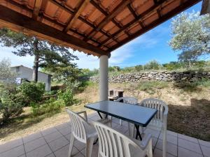 un patio con mesa, sillas y pared de piedra. en Village de gîtes La Fontinelle en Bessas