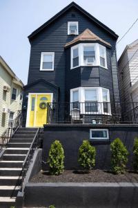 a black house with a yellow door and stairs at Rainforest Retreat 20m to NYC FREE Parking in Bayonne