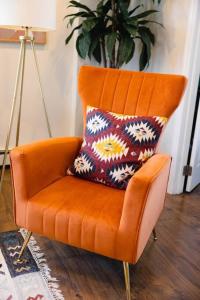 an orange chair with a pillow in a room at Rainforest Retreat 20m to NYC FREE Parking in Bayonne
