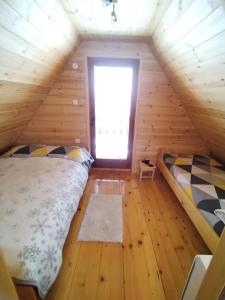 a bedroom with two beds in a wooden cabin at Fruskogorske brvnare in Velika Remeta