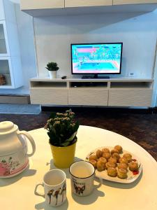 une table avec des tasses, un plateau de pâtisseries et une télévision dans l'établissement Trietje, à Gand