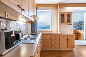 una cocina con armarios de madera y una gran ventana en Apt Sellablick, en Maranza