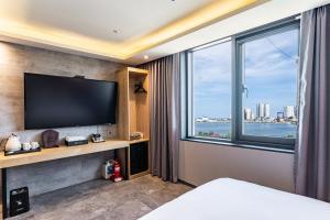 a bedroom with a flat screen tv and a large window at Sokcho Business Hotel CAMEL in Sokcho