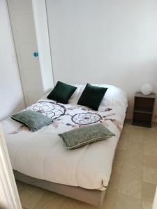 łóżko z zielonymi poduszkami w pokoju w obiekcie LE FLORIDE B Folco de baronchelli w mieście Le Grau-du-Roi