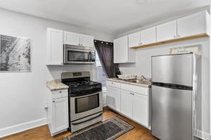 uma cozinha com armários brancos e um frigorífico de aço inoxidável em Whimsical Two em Bayonne