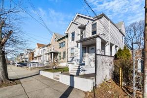 a white house on a street with houses at The Whimsical Estate in Bayonne