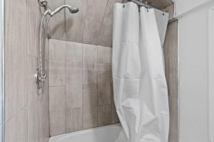 a shower with a white shower curtain in a bathroom at The Whimsical Estate in Bayonne