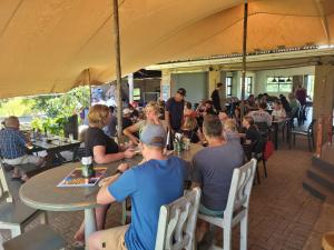 a group of people sitting at tables in a restaurant at OppiePlaas Country Estate in Haga-Haga