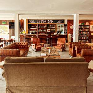 biblioteca con sillones y sillas de cuero en Hotel Lunajuim en El Chaltén