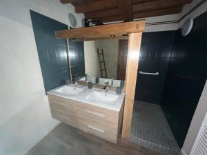 a bathroom with two sinks and a mirror at Gîte Entre Sources et Sapins 