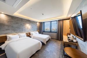 two beds in a hotel room with a large window at Sokcho Business Hotel CAMEL in Sokcho