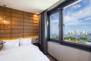 a bedroom with a bed and a large window at Sokcho Business Hotel CAMEL in Sokcho