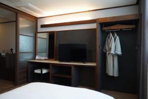 Schlafzimmer mit einem Schreibtisch, einem TV und einem Bett in der Unterkunft Sacheon Grand Tourist Hotel in Sacheon
