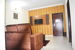 sala de estar con silla y TV en la pared en DAVIS HOTEL AND SUITES, en Port Harcourt
