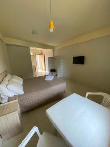 1 dormitorio con 1 cama, mesa y sillas en Lebanon Praia Hotel en Tramandaí