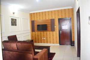 a living room with a couch and a television on a wall at DAVIS HOTEL AND SUITES in Port Harcourt