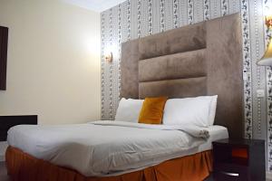 ポートハーコートにあるDAVIS HOTEL AND SUITESのベッドルーム1室(大型ベッド1台、ヘッドボード付)