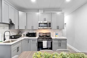 a kitchen with white cabinets and a stove and a table at Modern Dream Loft in Bayonne