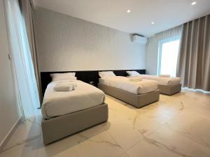 two beds and a couch in a room at Mayfair by Premier Suites MT in Is-Swieqi